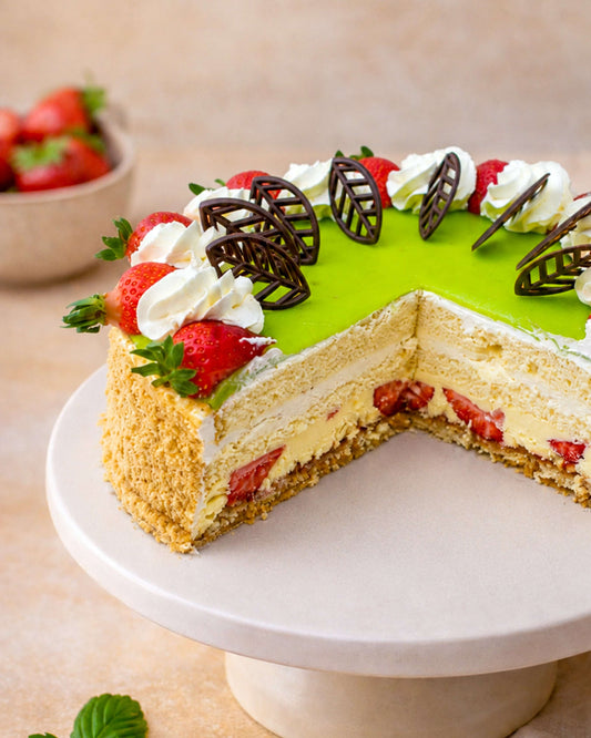 Banana Strawberry Gateau with layers of sponge, custard cream, bananas, strawberries, topped with marzipan and chocolate leaves.