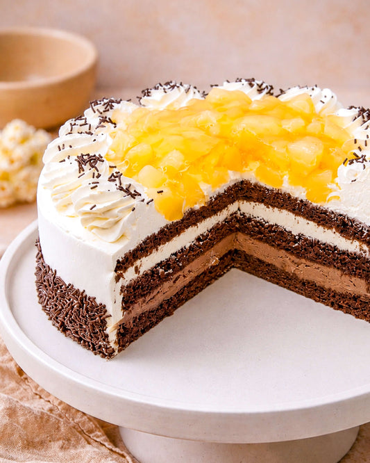 Chocolate pear gateau with layers of chocolate sponge, fresh cream, and topped with pear pieces.