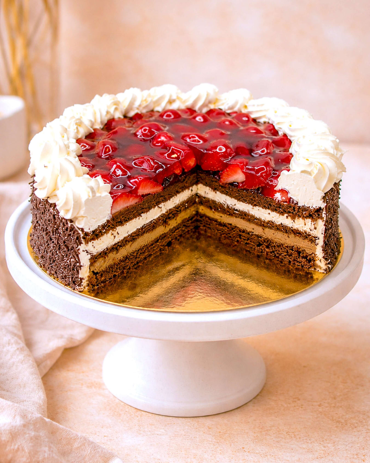 Chocolate Strawberry Gateau with layers of chocolate sponge, cream, and fresh strawberries on a cake stand.