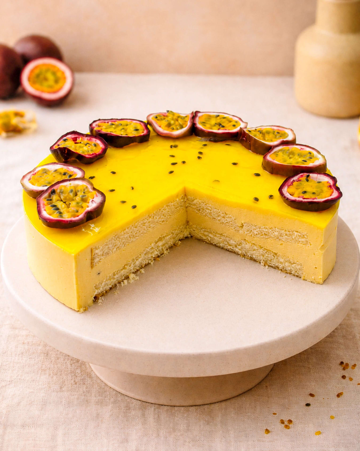 A vibrant passion fruit mousse cake topped with fresh passion fruit slices, showcasing a light sponge base and creamy filling.