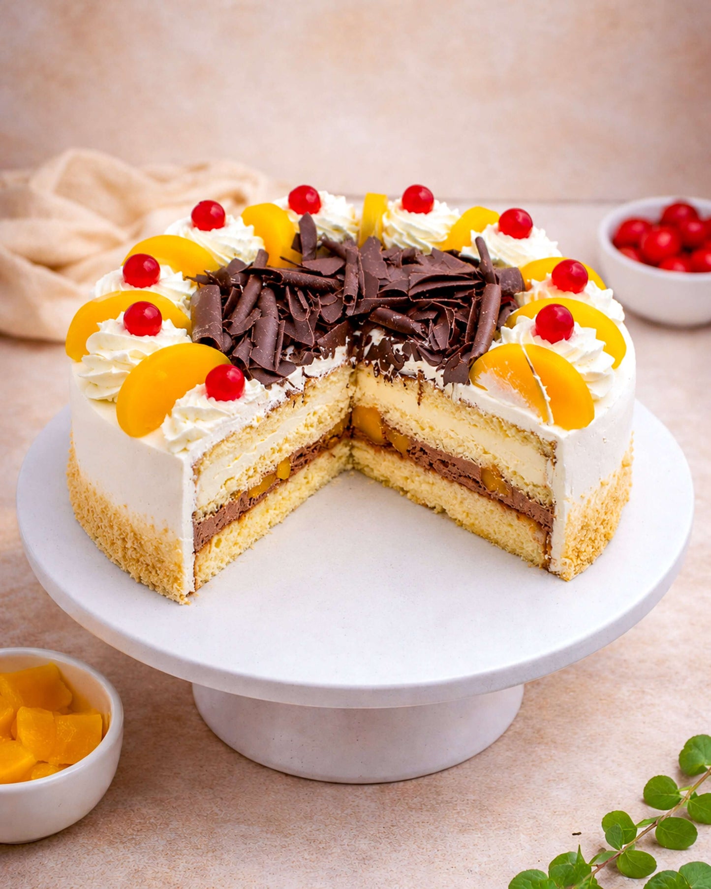 Peach Gateau with layers of vanilla sponge, fresh cream, peaches, and chocolate, beautifully decorated with cherries.