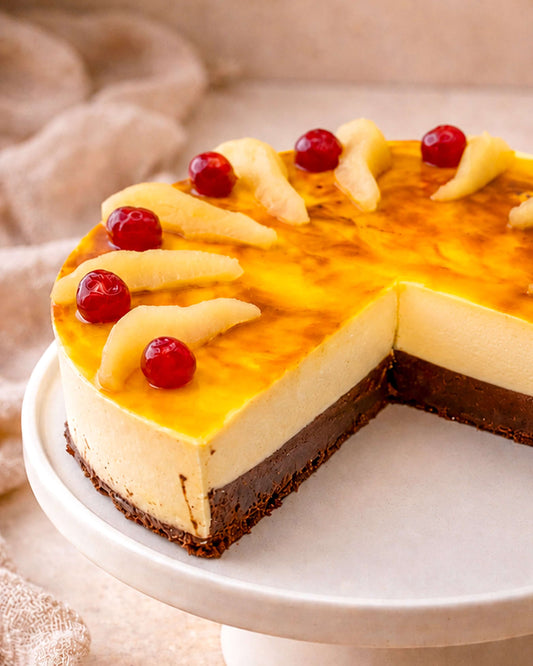 Pear caramel mousse on a cake stand, featuring layers of chocolate sponge, pear slices, and cherries.