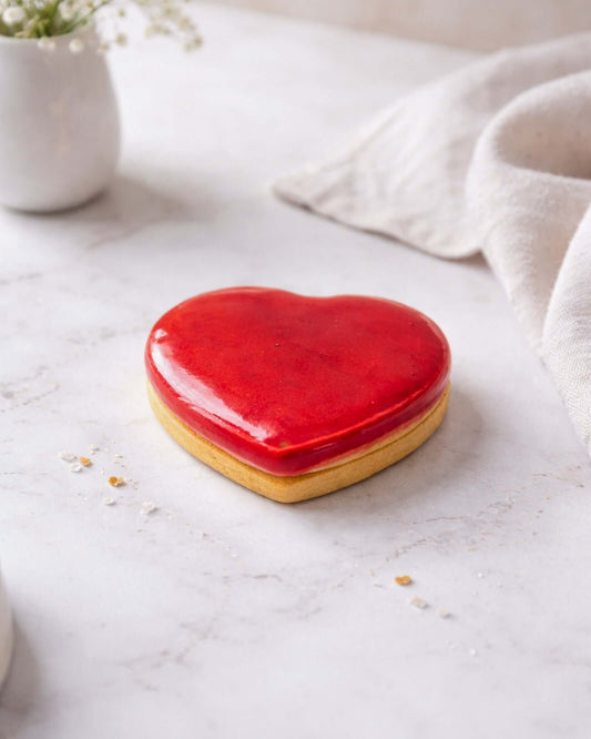Raspberry Heart biscuit shaped like a heart, featuring a bright red glaze on a golden base.