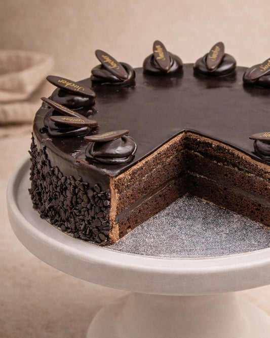 Sachertorte with layers of chocolate sponge and buttercream, topped with glossy ganache and chocolate decorations.
